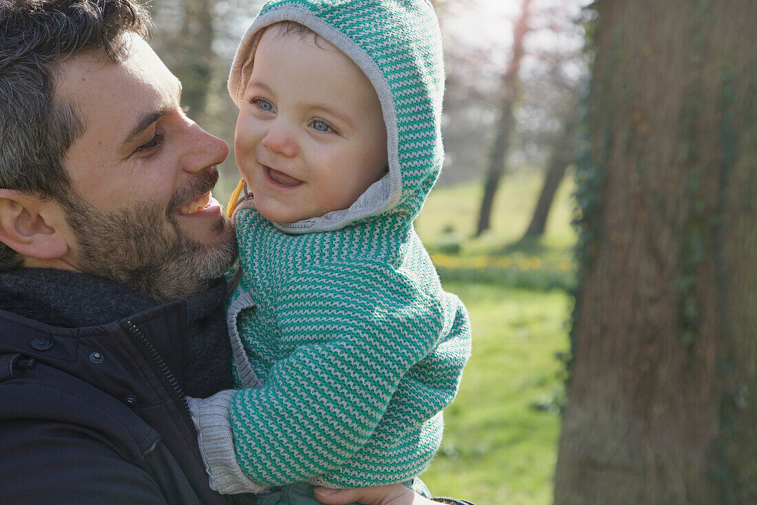 Smiling Man Holding Baby Boy Outdoors