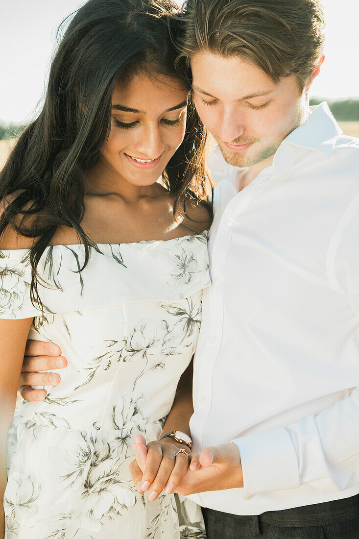 Man Holding Woman's Hand Looking at Engagement Ring