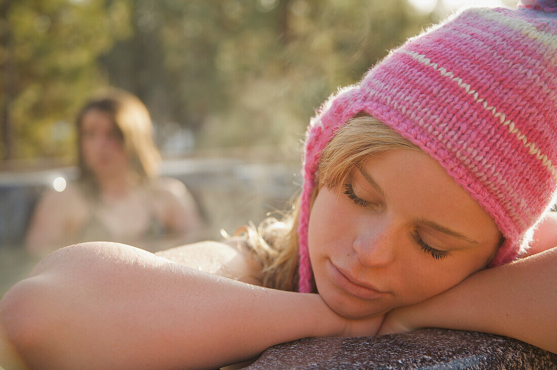 Young woman resting on the edge of a hot tub with her eyes closed