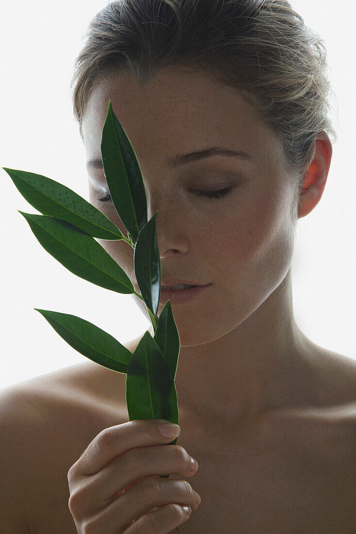 Woman Holding Green Leafed Twig in front of her Face