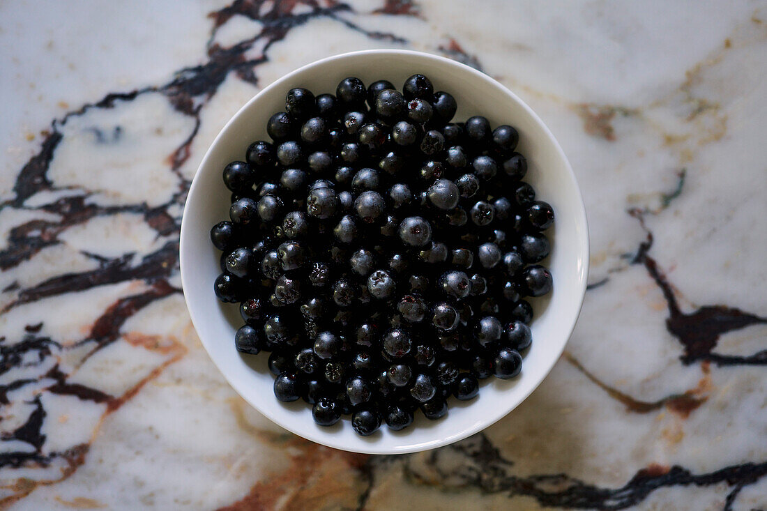 Blick von oben Stilleben schwarze Aroniabeeren in Schale auf Granittheke