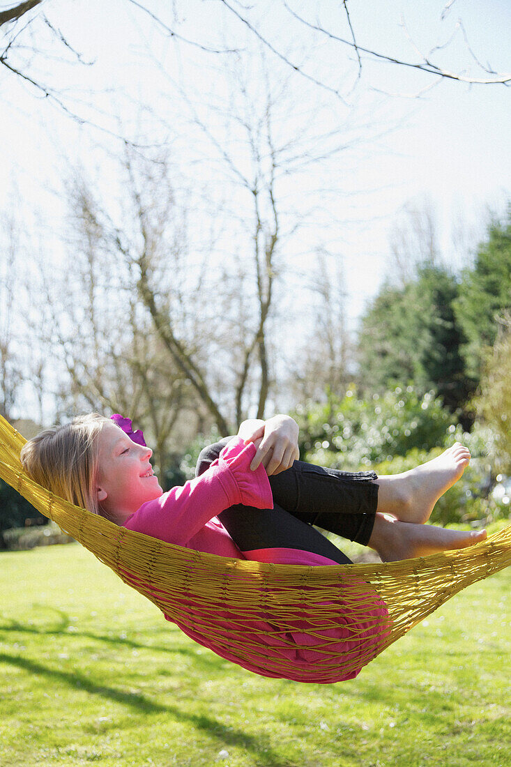 Profile of a girl lying on a hammock hugging her knees