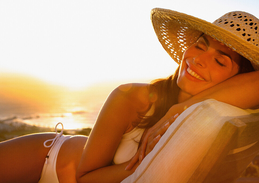 Smiling Woman Wearing Straw Hat Lying on Sun Lounger