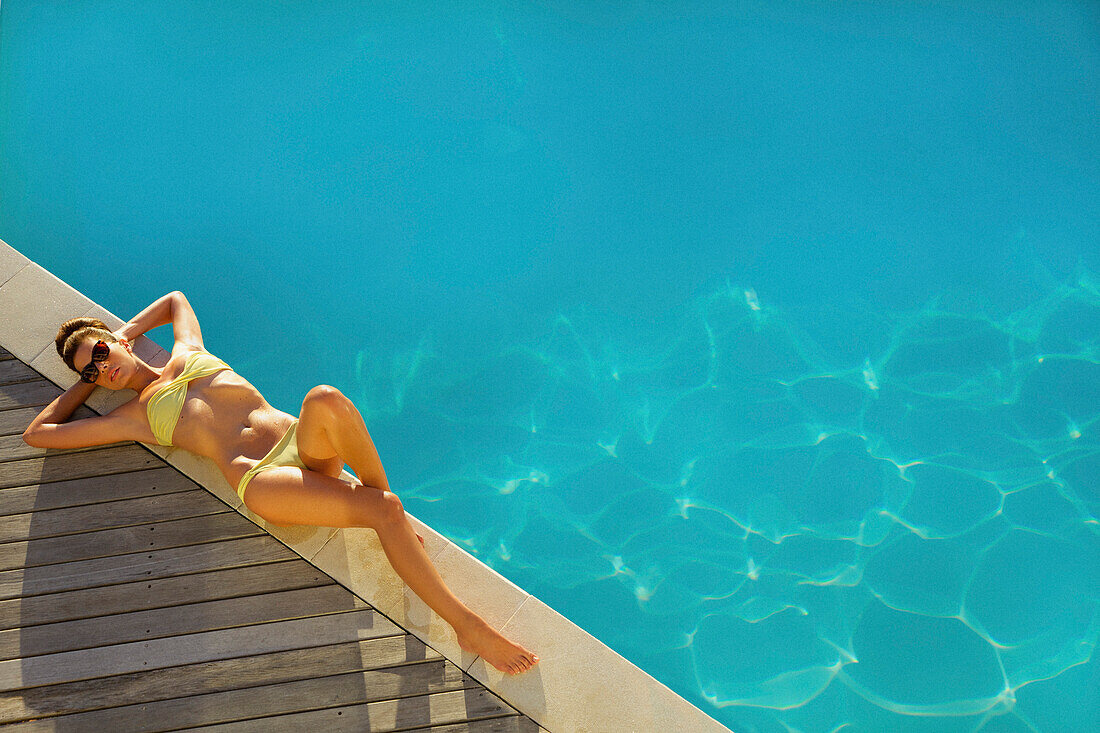 Woman Sunbathing by Swimming Pool, High Angle View