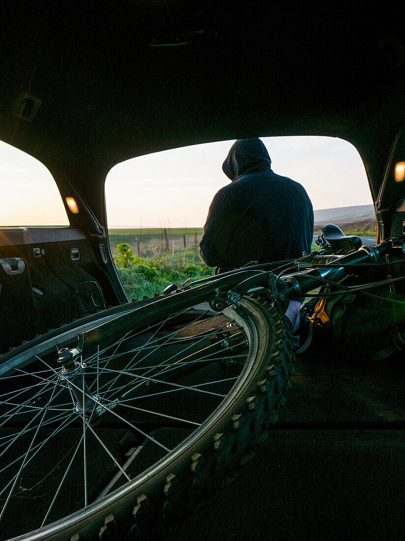 Fahrrad im Kofferraum mit Mann im Hintergrund