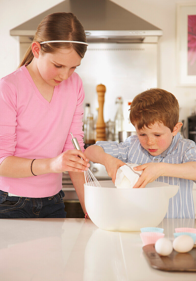 Girl and young boy preparing cupcakes