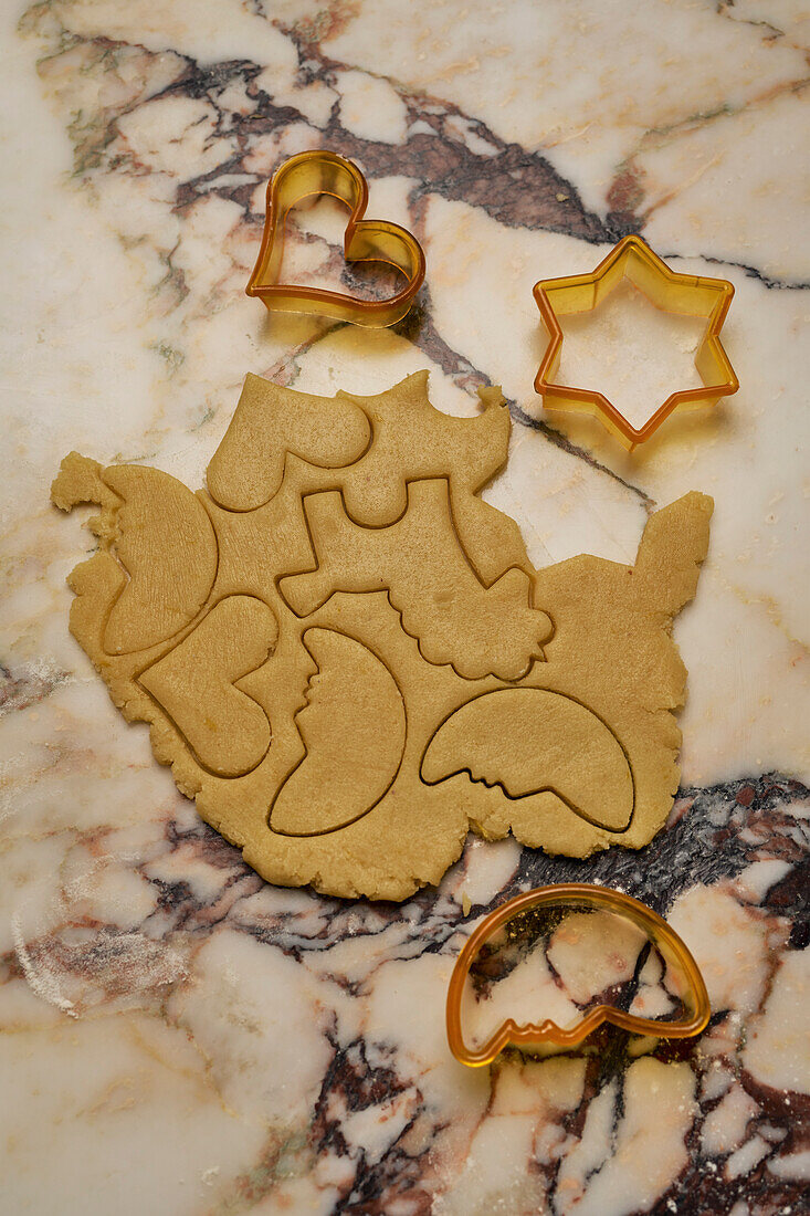 Cookie cutters and cookie dough on marble surface