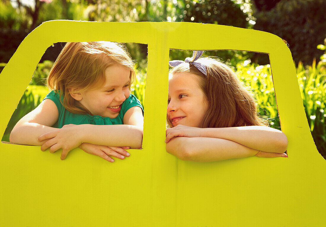 Young Girls Leaning out of Cardboard Car Window