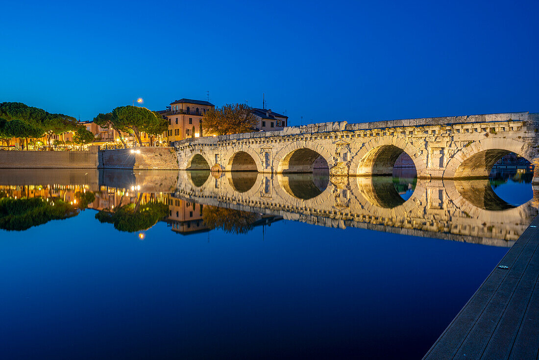 Blick auf die Ponte di Tiberio, die sich im Kanal von Rimini im Stadtteil Borgo San Giuliano in der Abenddämmerung spiegelt, Rimini, Emilia-Romagna, Italien, Europa