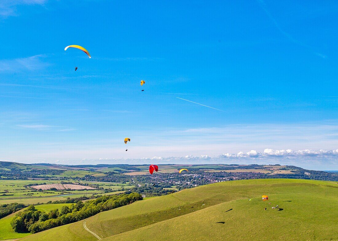 Gleitschirmflieger am Mount Caburn, die über der Grafschaftsstadt Lewes, East Sussex, England, Vereinigtes Königreich, Europa fliegen