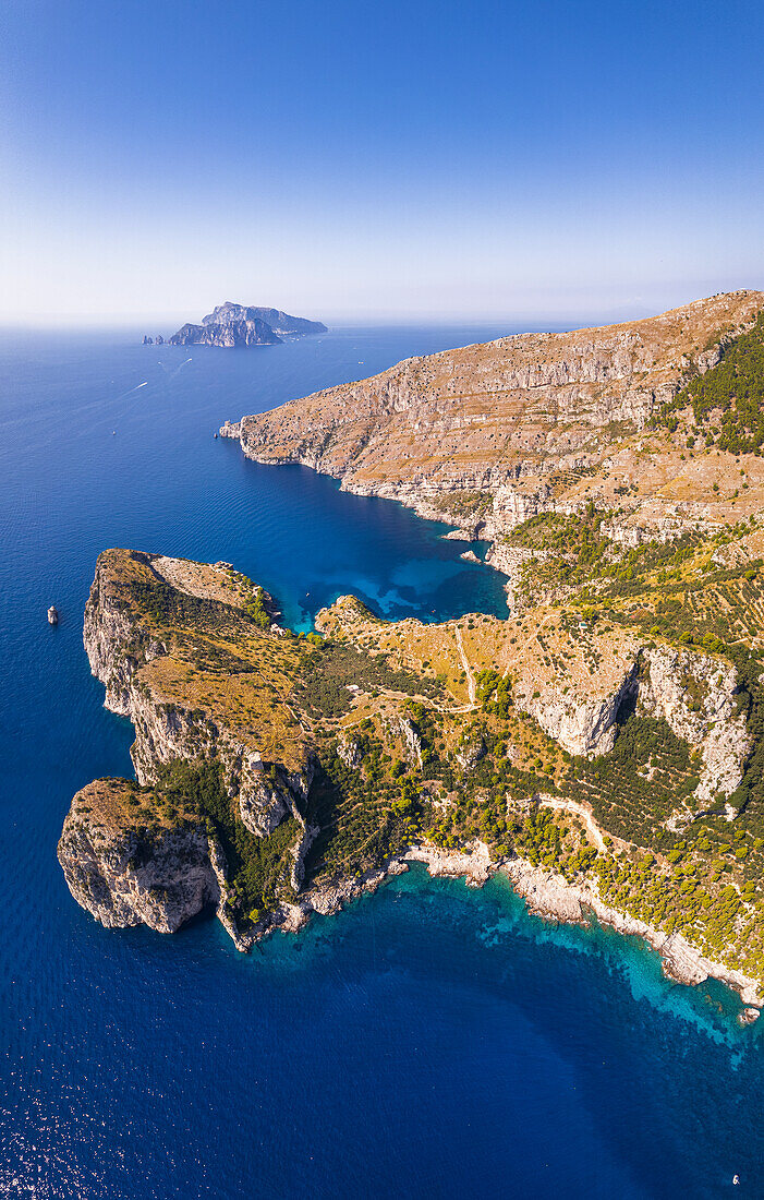 Panoramablick auf die Felsküste von Punta Campanella und die Bucht von Ieranto mit der Insel Capri im Hintergrund, Amalfiküste, Provinz Neapel, Region Kampanien, Tyrrhenisches Meer, Süditalien, Europa