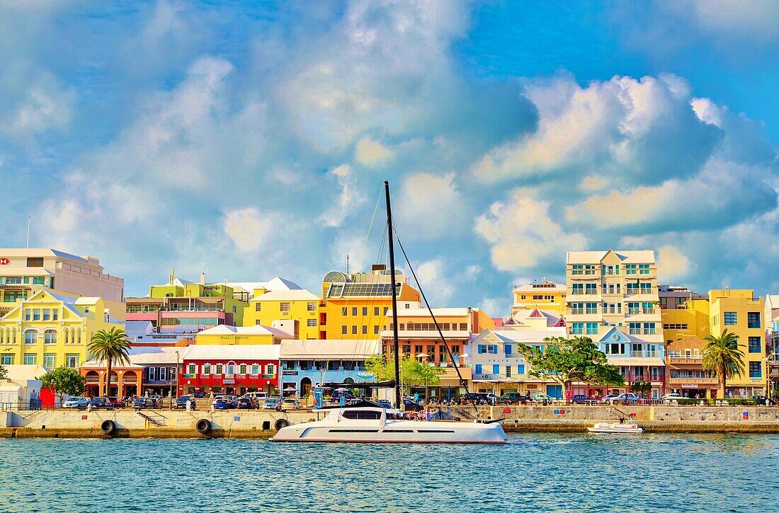 Catamaran passing pastel coloured buildings on Front Street, Hamilton, Bermuda, Atlantic, North America
