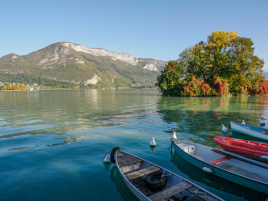 Berge, kleine Boote und Herbstfarben auf dem Annecy-See, Annecy, Haute-Savoie, Frankreich, Europa