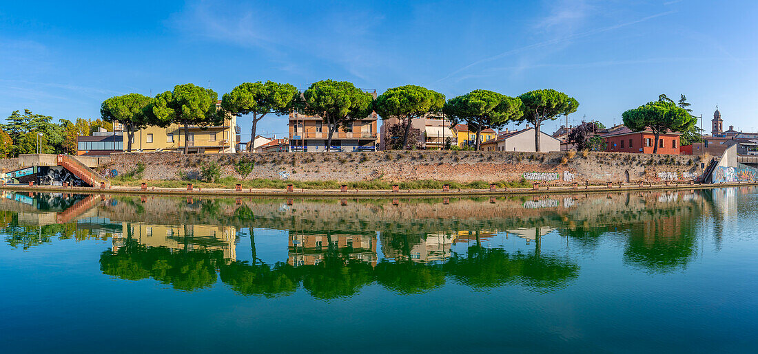 Blick auf Gebäude und Pinienbäume, die sich im Kanal von Rimini spiegeln, Rimini, Emilia-Romagna, Italien, Europa