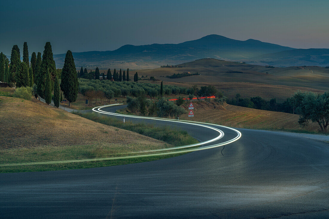 View of car trail lights in Tuscan landscape near Pienza at dusk, Pienza, Province of Siena, Tuscany, Italy, Europe