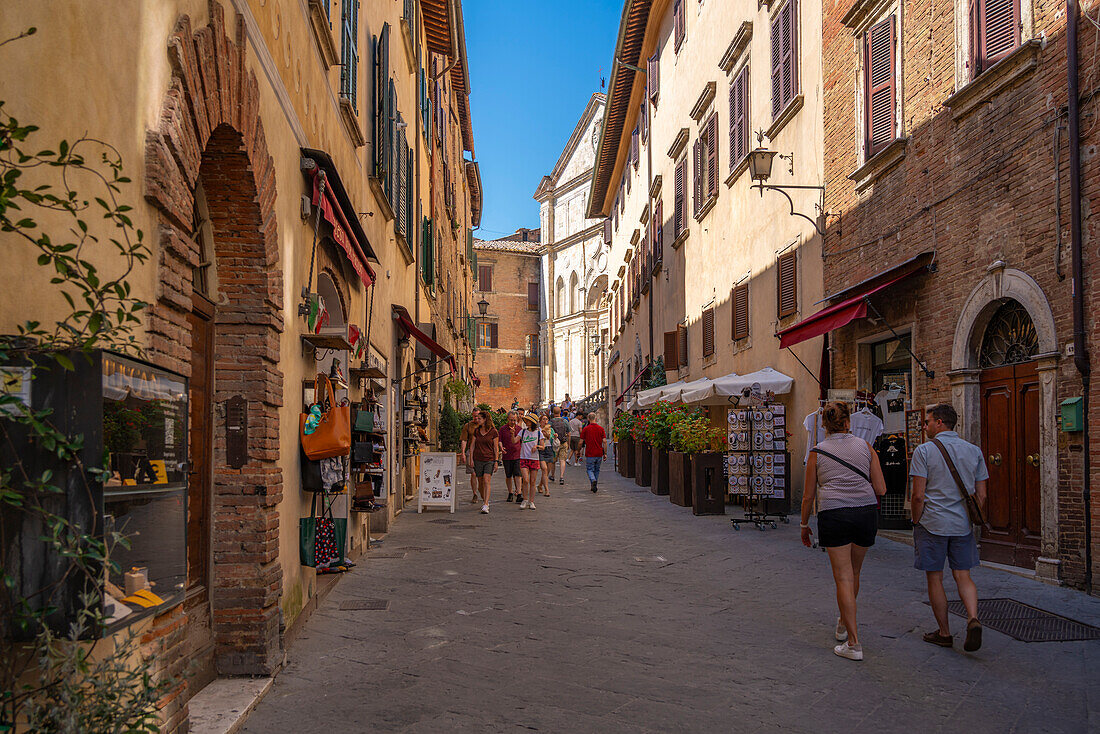 Blick auf Geschäfte und Einkäufer in einer engen Straße in Montepulciano, Montepulciano, Provinz Siena, Toskana, Italien, Europa