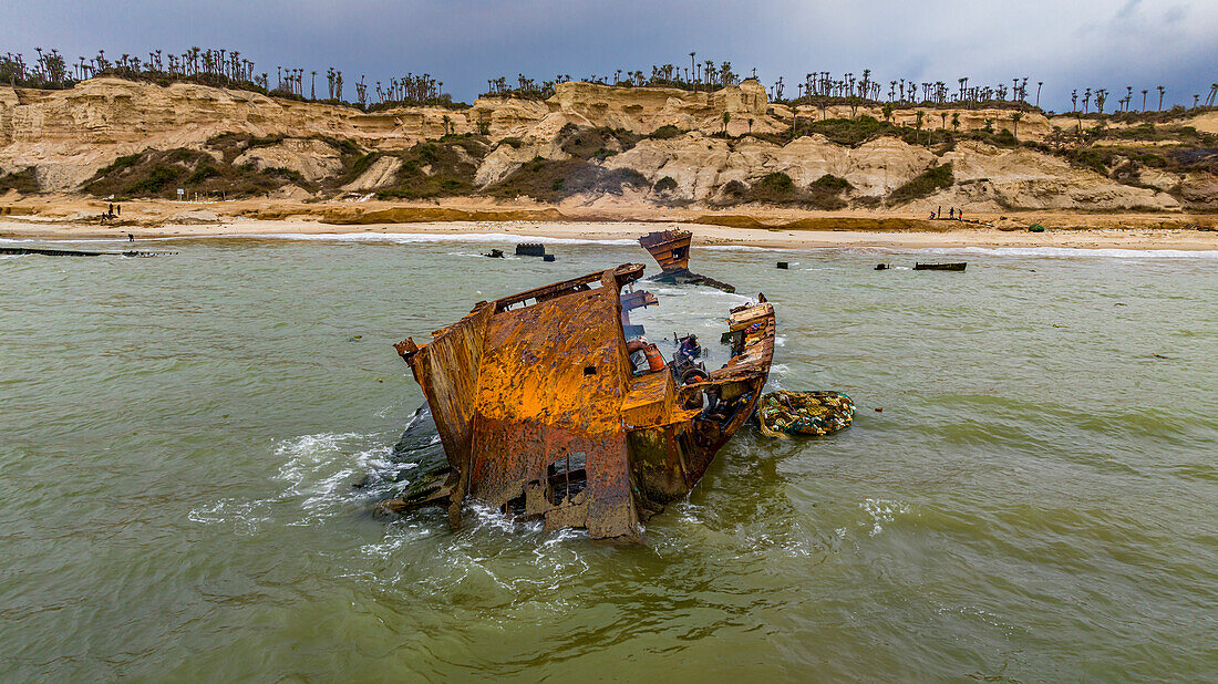 Männer zerlegen ein Boot am Strand des Schiffswracks, Bucht von Santiago, Luanda, Angola, Afrika