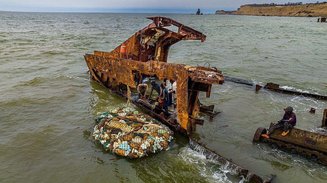 Men dismantling a boat on Shipwreck beach, Bay of Santiago, Luanda, Angola, Africa