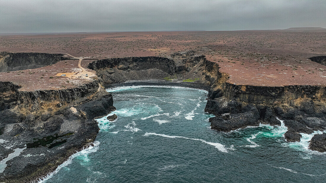 Luftaufnahme der wilden Küstenlinie mit Basaltbecken an der Atlantikküste, Dombe Grande, Namibre, Angola, Afrika