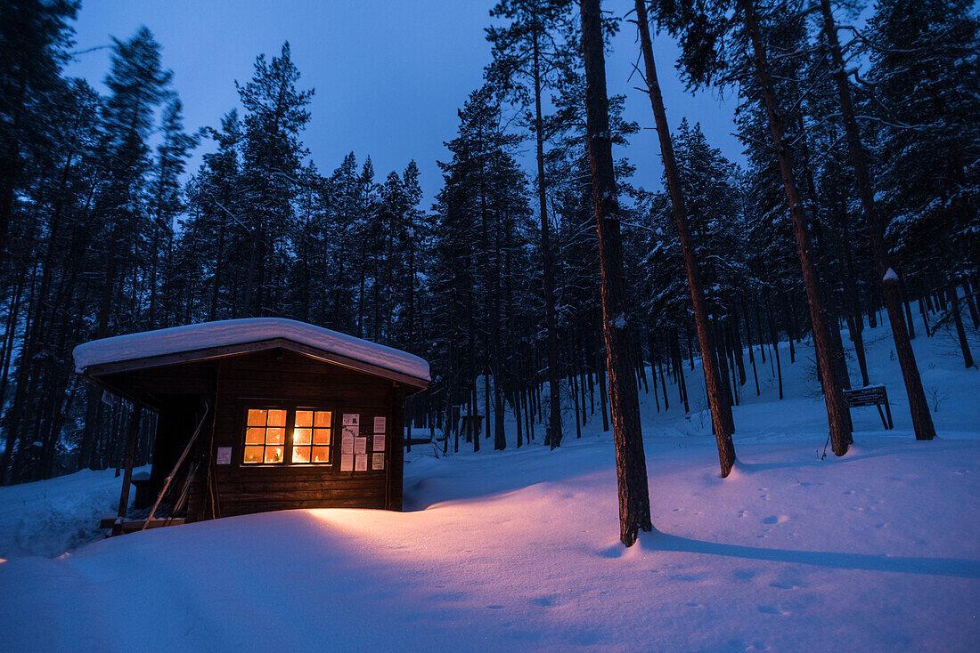 Blockhütte mit Feuer im Inneren, Winter, Lemmenjoki Nationalpark, Finnland, Europa