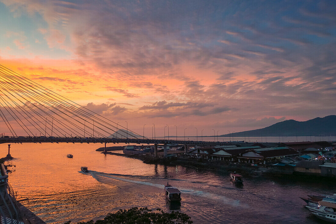Hafen von Manado und Soekarno-Brücke mit der Insel Manadotua dahinter bei Sonnenuntergang in der Provinzhauptstadt von Sulawesis hohem Norden, Manado, Nordsulawesi, Indonesien, Südostasien, Asien