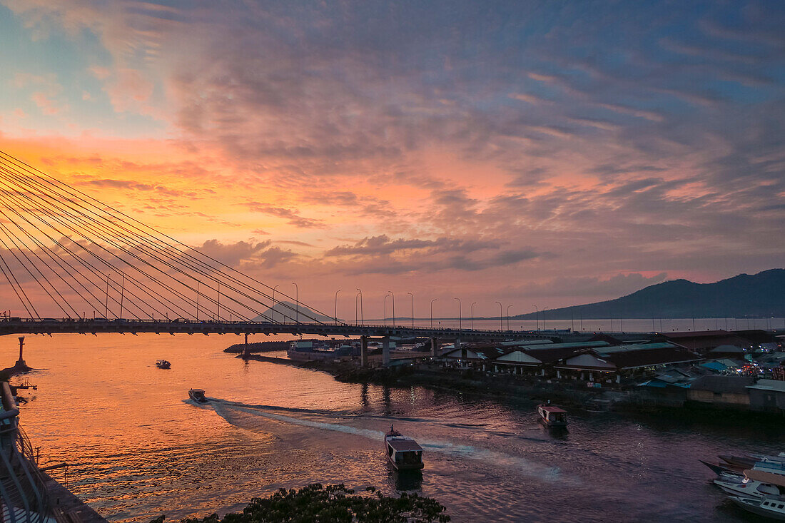 Manado port and Soekarno Bridge with Manadotua Island beyond at sunset in provincial capital of Sulawesi's far north, Manado, North Sulawesi, Indonesia, Southeast Asia, Asia