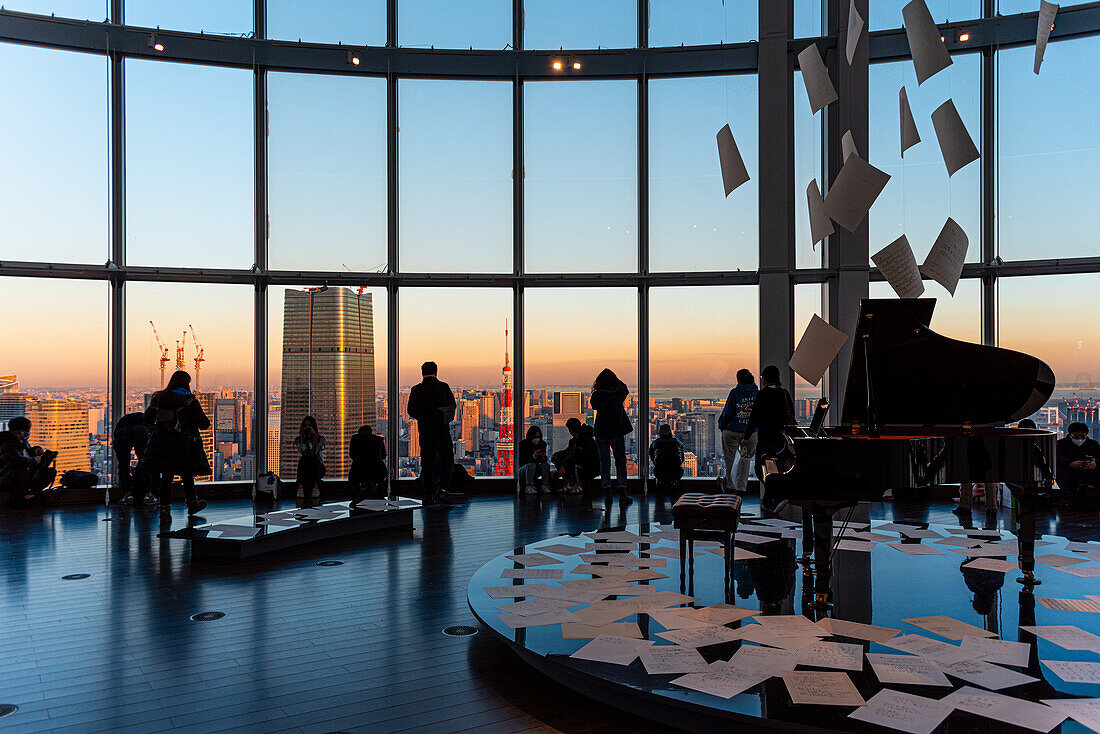 Panoramic view through a big window in Roppongi Hills, with visitors enjoying the evening light, silhouettes and grand piano, Tokyo, Honshu, Japan, Asia