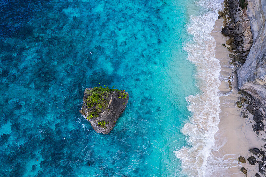 Luftaufnahme von Suwehan weißer Sandstrand mit türkisfarbenem Meerwasser und dem großen Felsen (Meeresstapel) im Meer von einer Drohne aus gesehen, Nusa Penida, Klungkung regency, Bali, Indonesien, Südostasien, Asien