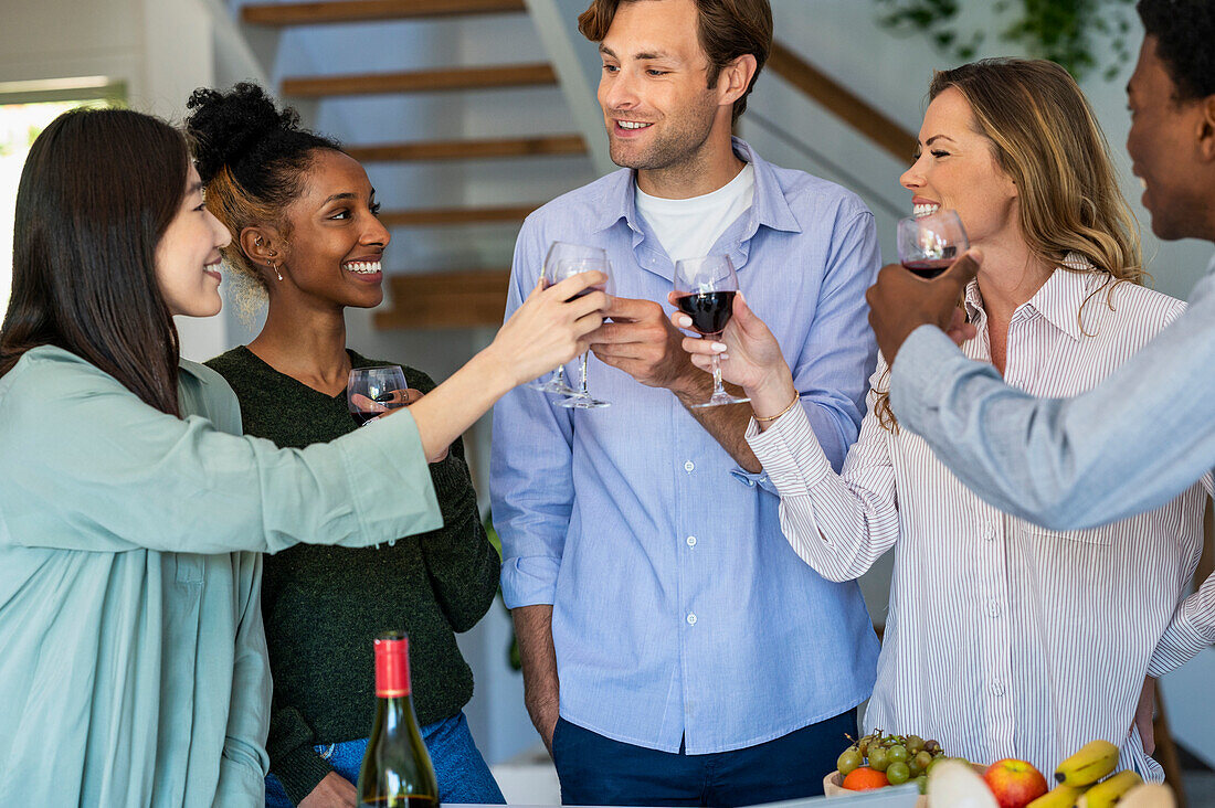 Gruppe von Freunden stößt mit Weingläsern an, während sie in einem Haus abhängen