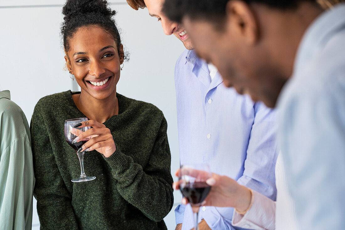 Fröhliche junge erwachsene Frau trinkt Wein während eines Freundestreffens