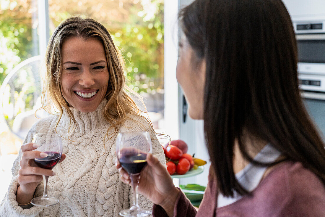 Two friends talking during reunion while drinking wine