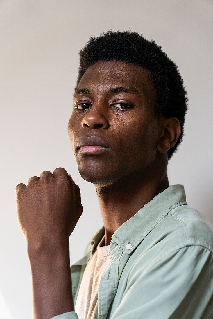 Side view portrait of young adult man looking to the camera while raising fist