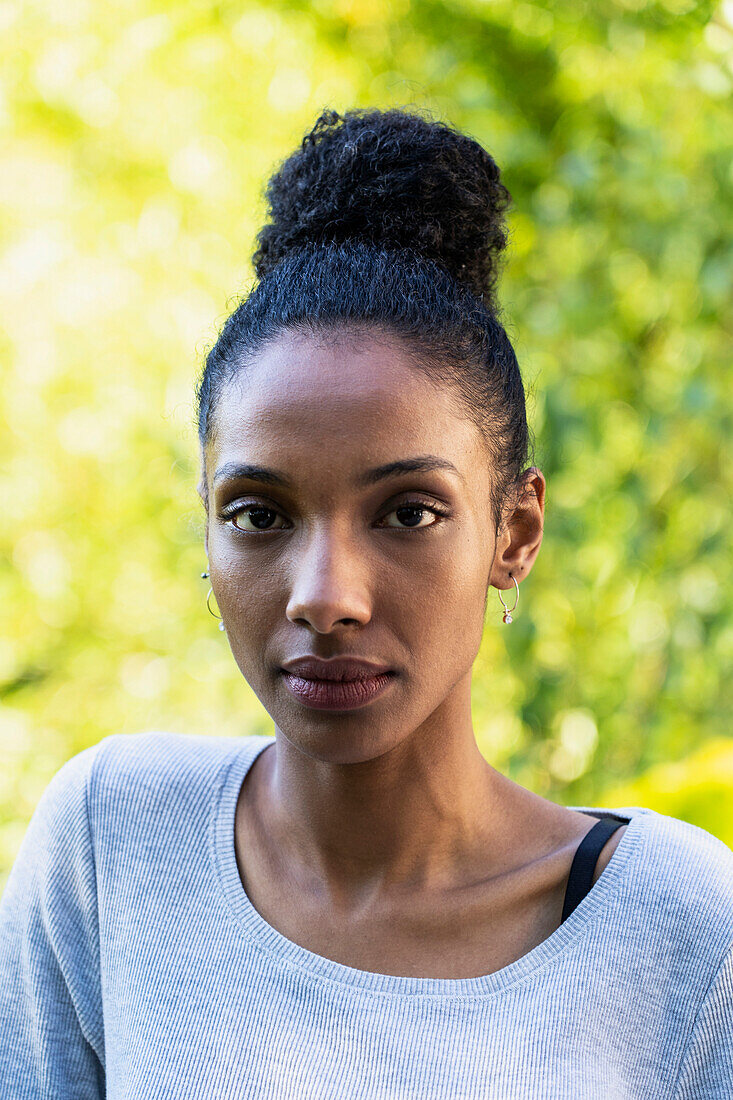 Front view portrait of young adult woman looking at the camera standing outdoors