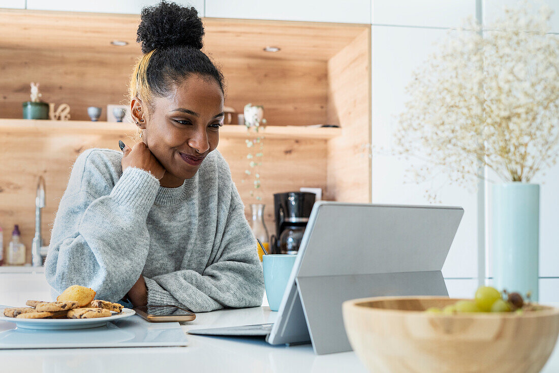 Frau hält eine Webkonferenz auf einem digitalen Tablet in der Küche ab