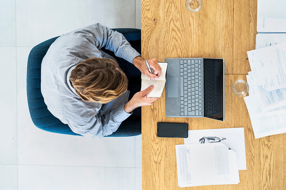 Advertising agency worker taking notes while sitting at desk