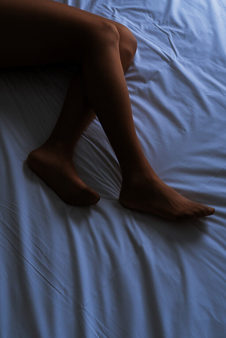 Unidentified person's legs lying in bed