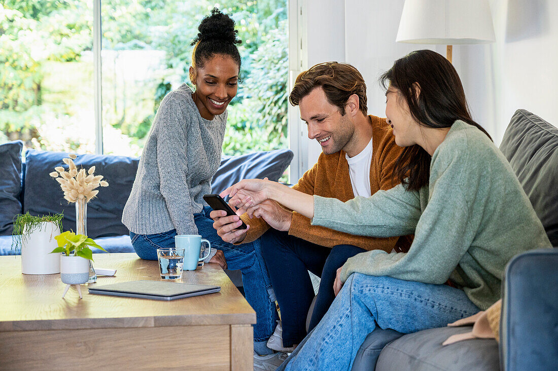 Small group of friends gathered in living room while using smart phone