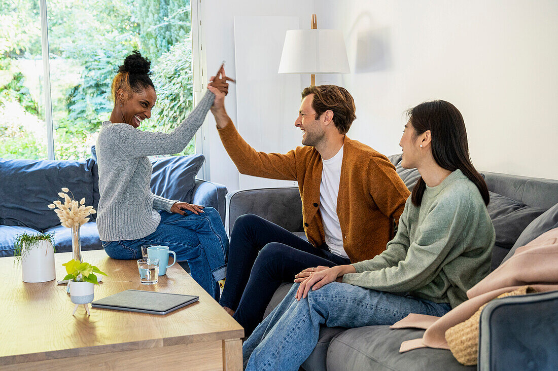 Adult man high fiving with friend during reunion at living room