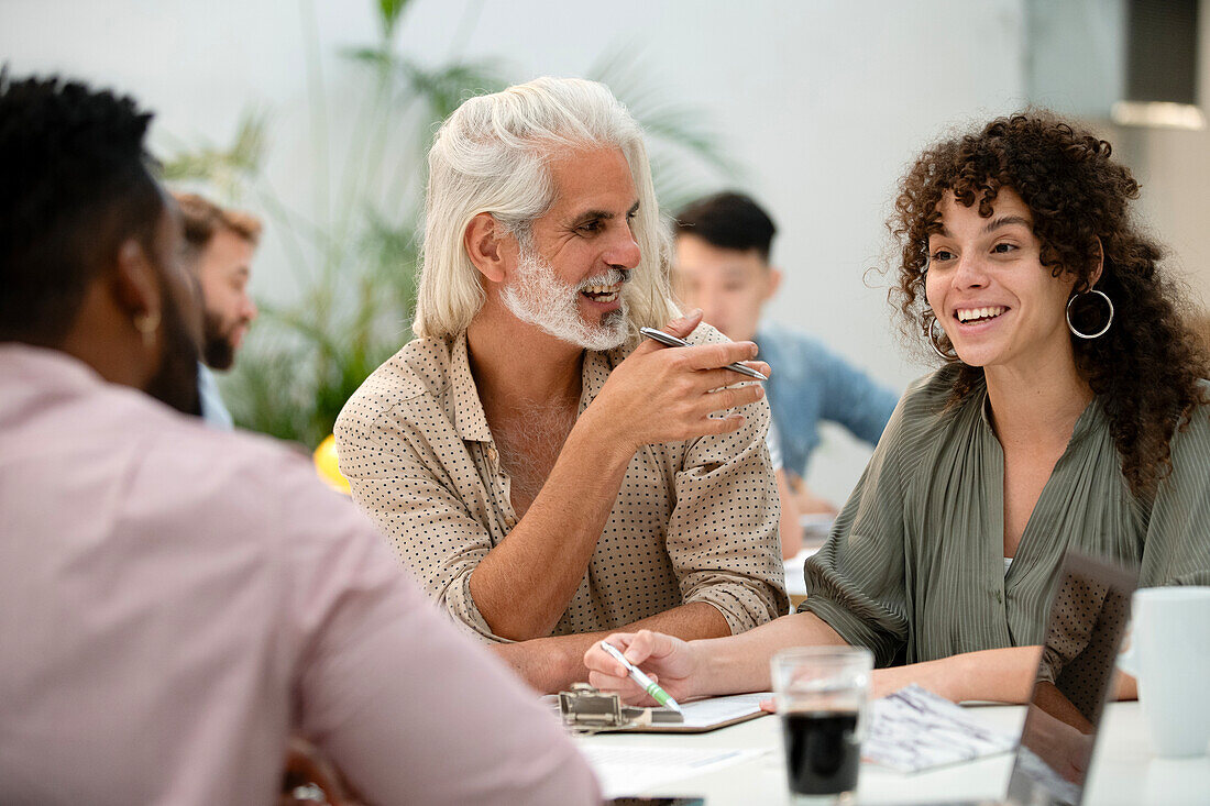 Adult businessman listening to female coworker during meeting