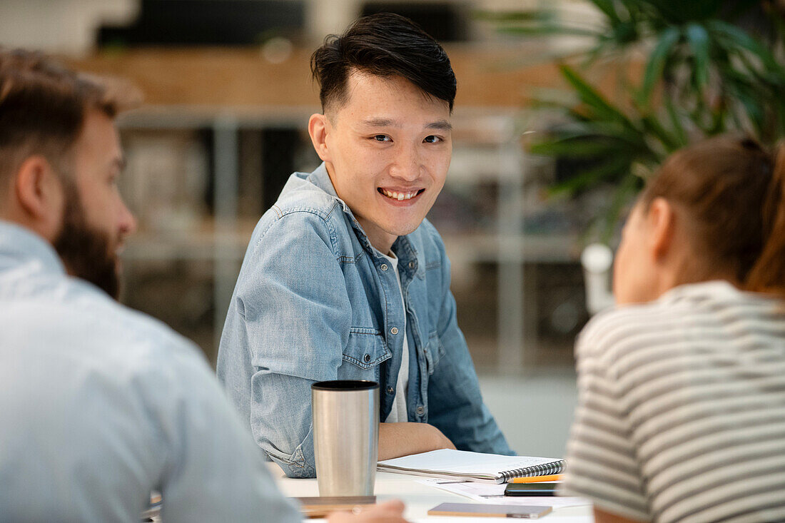 Young adult male architect looking at the camera while sitting at table