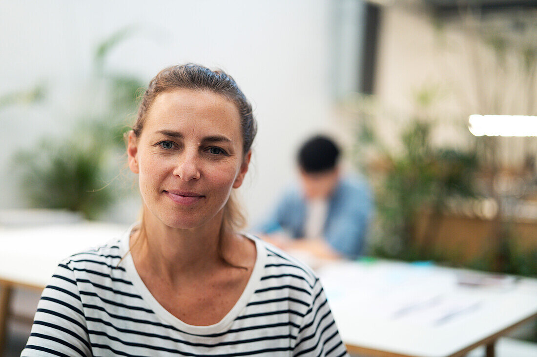 Architektin schaut in die Kamera, während sie im Büro steht