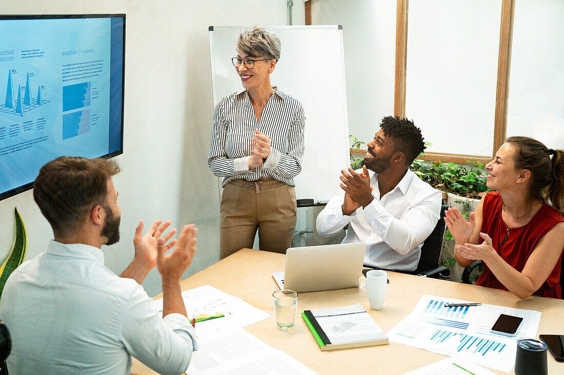 Coworkers celebrating project presentation made by businesswomen