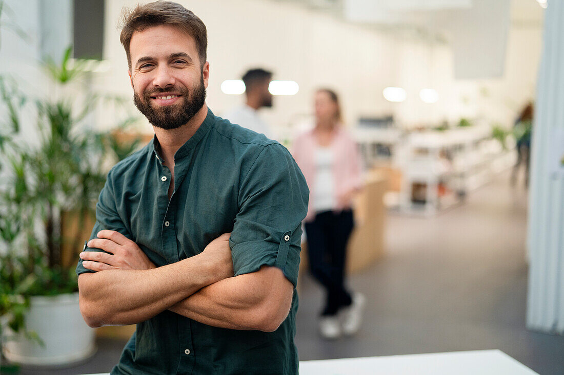 Adult male coworker leaning on table with crossed arms