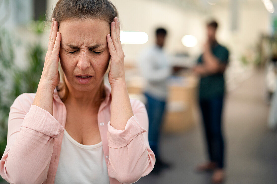 Adult woman with hands on face having a headache