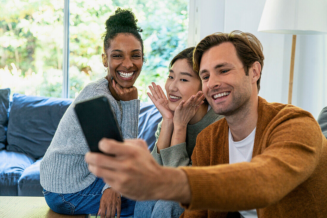 Small group of friends taking a selfie while sitting on sofa