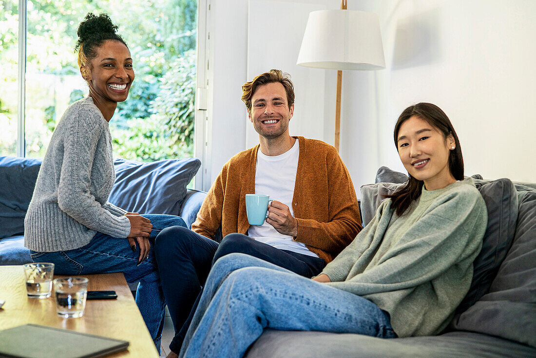 Small group of friends gathered in living room looking at the camera