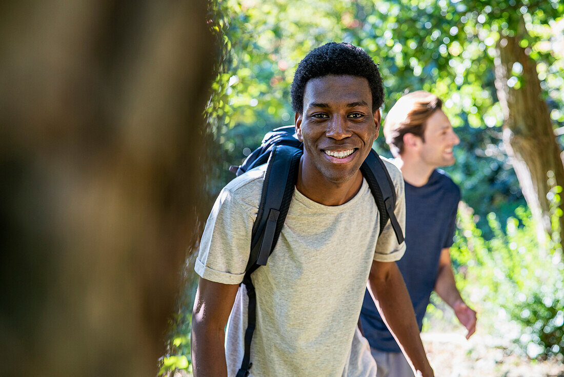 Young adult man wearing backpack looking at the camera during hiking with friends