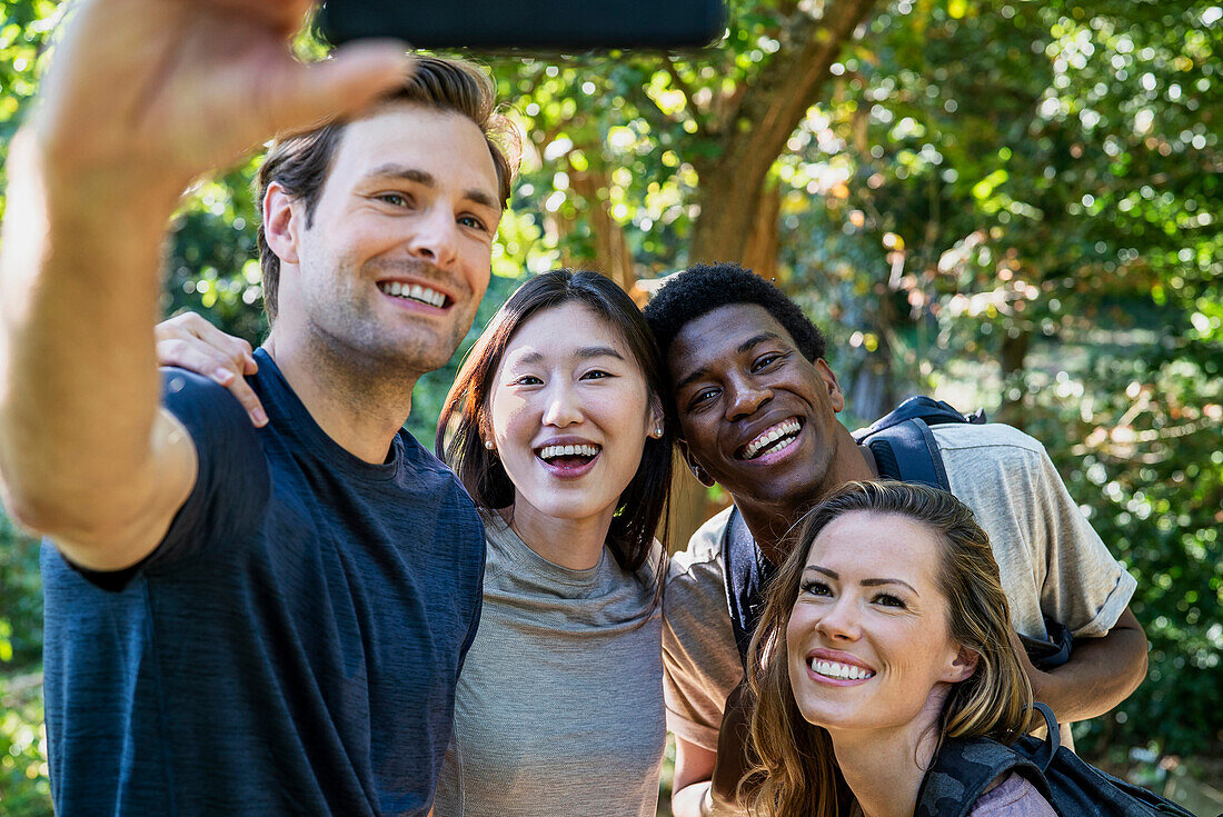 Young adult man taking a selfie with friends during hiking excursion