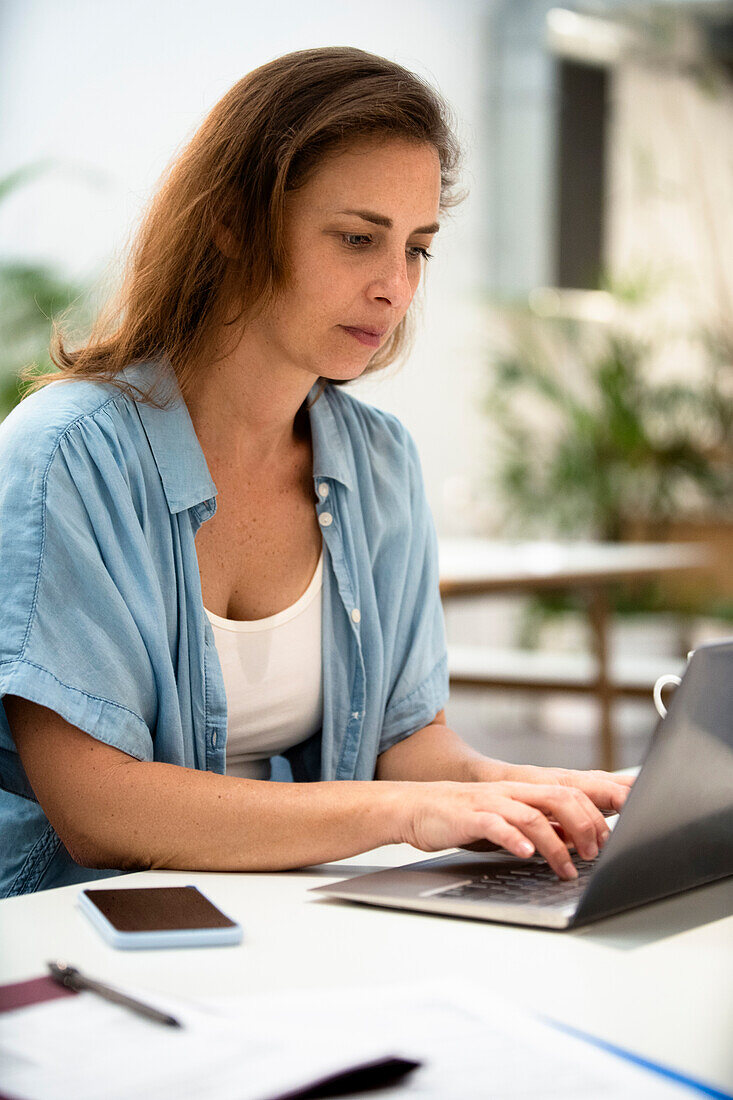 Adult woman using laptop while working on laptop at design studio