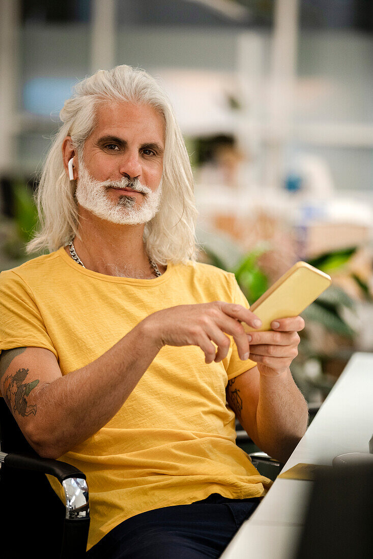 Male computer programmer looking at the camera while using smart phone